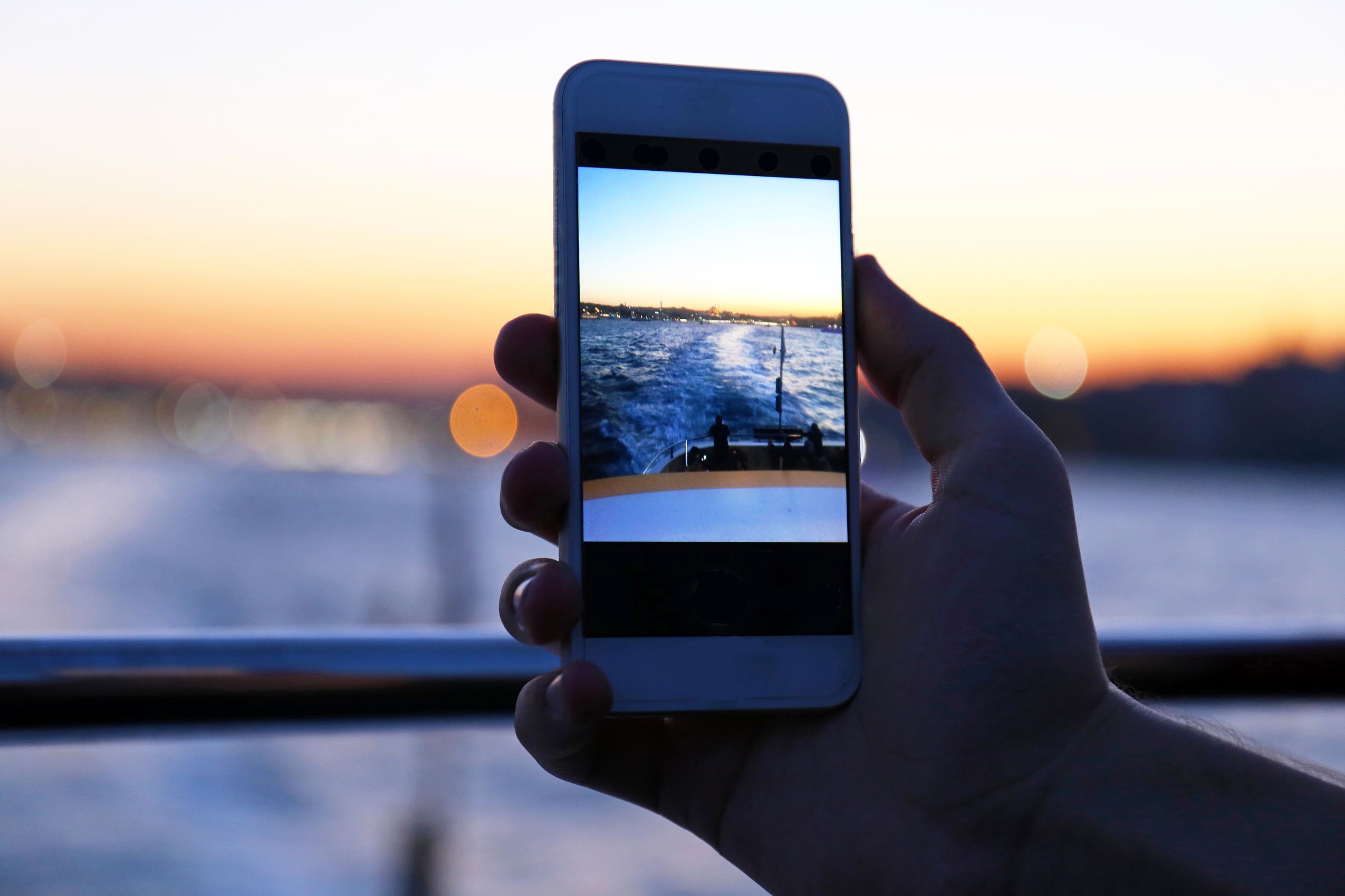 sunset with hand holding smartphone, taking a picture