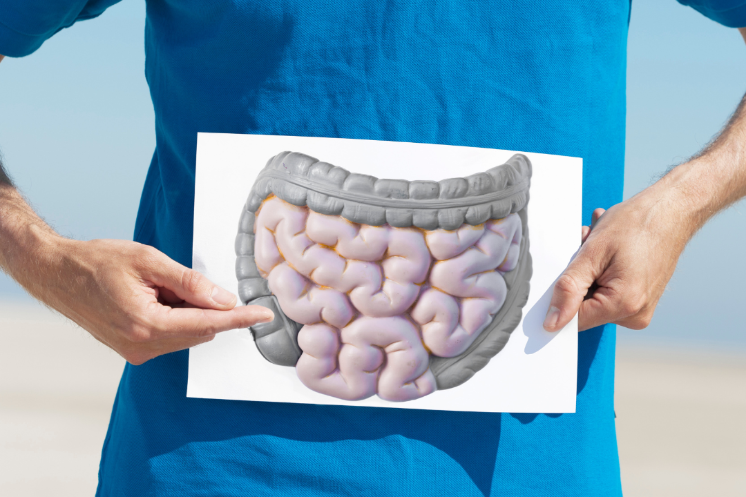 person in blue shirt holding image of intestines over bellly