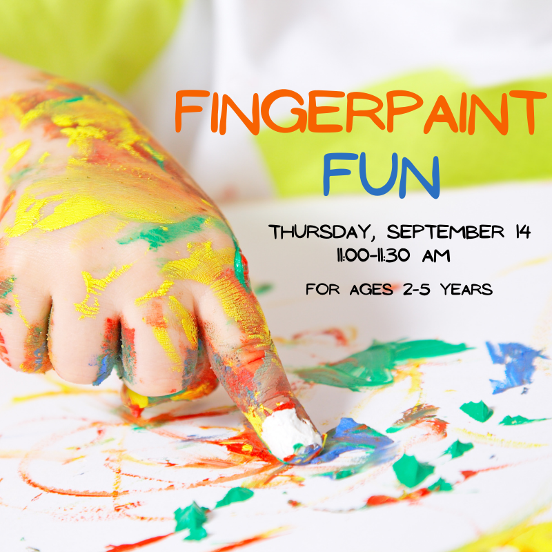 A hand covered in yellow, green, and orange paint finger painting on a white canvas.